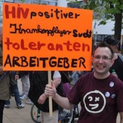 Sven H. auf einer Demo mit Schild: "HIV-positiver Krankenpfleger sucht toleranten Arbeitgeber"