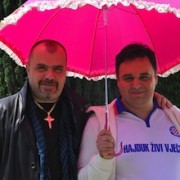 Zwei Männer unter einem pinkfarbenen Schirm