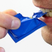 Aufreißen eines Kondoms mit Zähnen