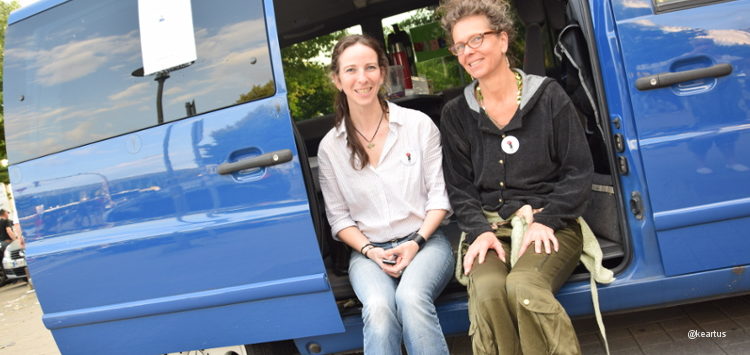 Zwei Beraterinnen sitzen vor dem blauen Bus des Projektes