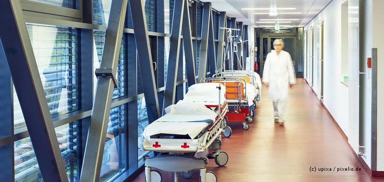 Flur im Krankenhaus mit zwei Betten und geschlossener Tür zur Ambulanz mit Arzt unscharf