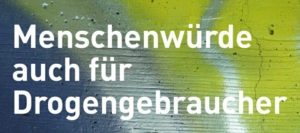 Eine bunt besprühte Wand, davor der Slogan "Menschenwürde auch für Drogengebraucher"