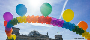 Eine Kette aus Luftballons in den Farben des Regenbogens vor dem Reichstagsgebäude
