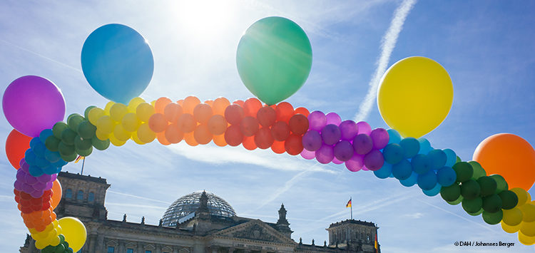 Eine Kette aus Luftballons in den Farben des Regenbogens vor dem Reichstagsgebäude