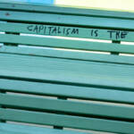 protest message against capitalism and the corona virus is written on a bench. outdoors