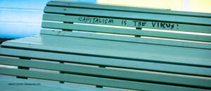 protest message against capitalism and the corona virus is written on a bench. outdoors