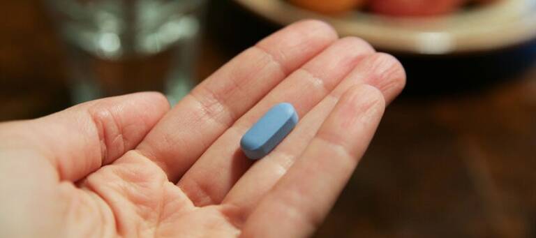 Hand mit blauer PrEP-Tablette