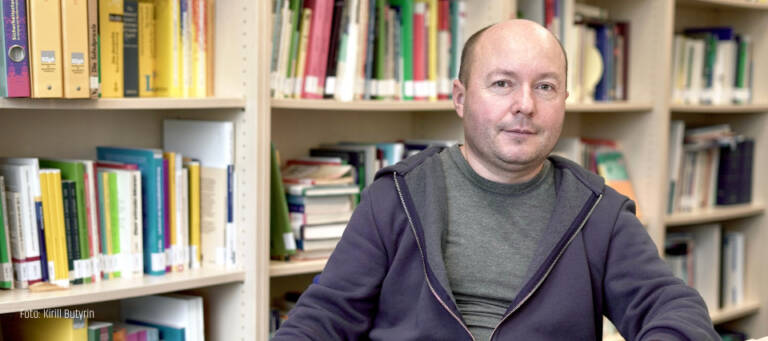 Porträt Dmitry Subtselny vor Bücherwand am Tisch sitzend