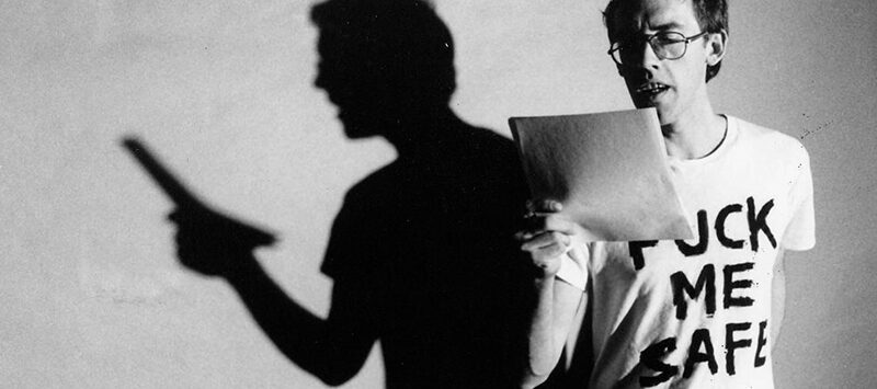 Video-Still mit David Wojnarowicz, Künstler und HIV-Aktivist, der ein T-Shirt trägt mit der Aufschrift 