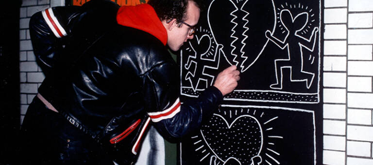 Keith Haring zeichnet ein Graffito an eine Wand. Standbild aus dem Film "The Universe of Keith Haring".