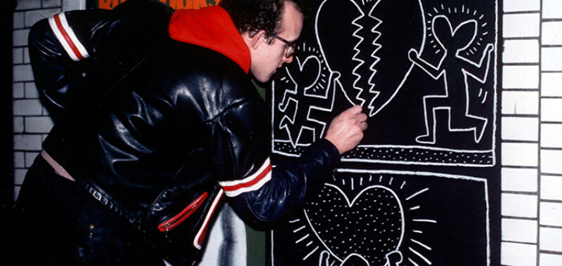 Keith Haring zeichnet ein Graffito an eine Wand. Standbild aus dem Film 