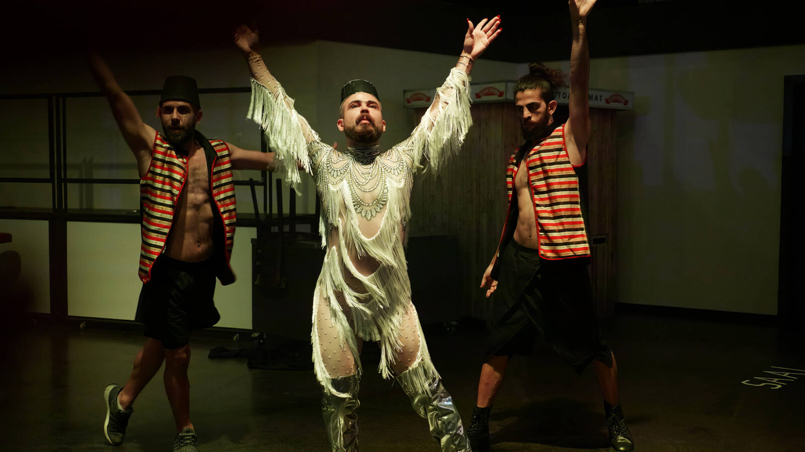 Drei Personen beim Tanz mit erhobenen Armen in nahöstlichen Gewändern