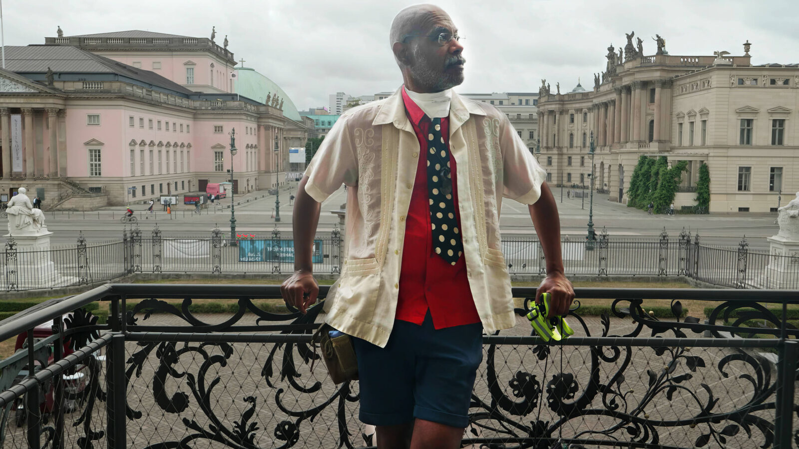 Person steht auf einem historischen Balkon an das Geländer gelehnt mit dem Rücken zu einem Berliner Platz