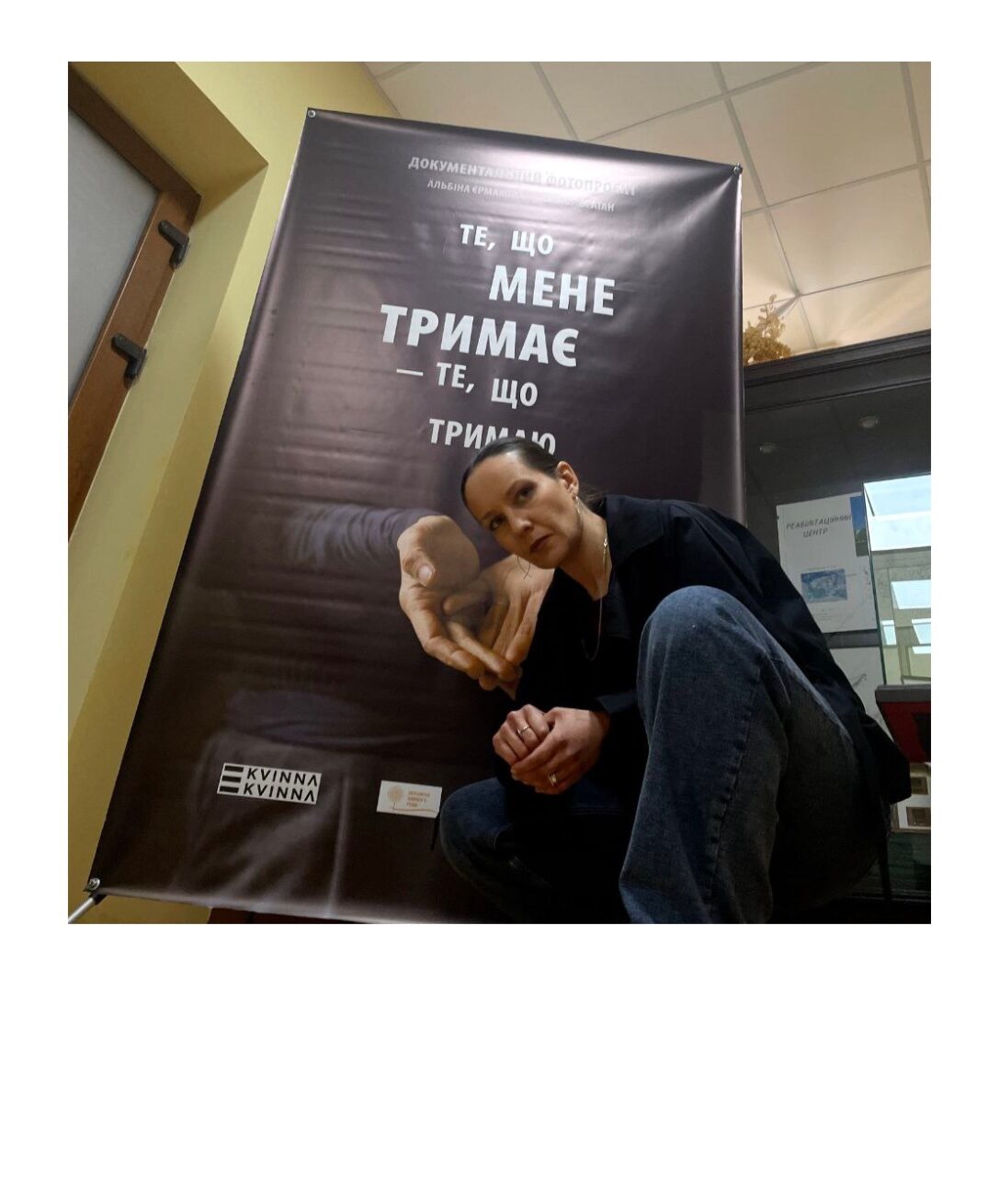 LGBTIQ* in der Ukraine: weibliche Person in dunkler KLeidung hockt vor einem großen Plakat: 