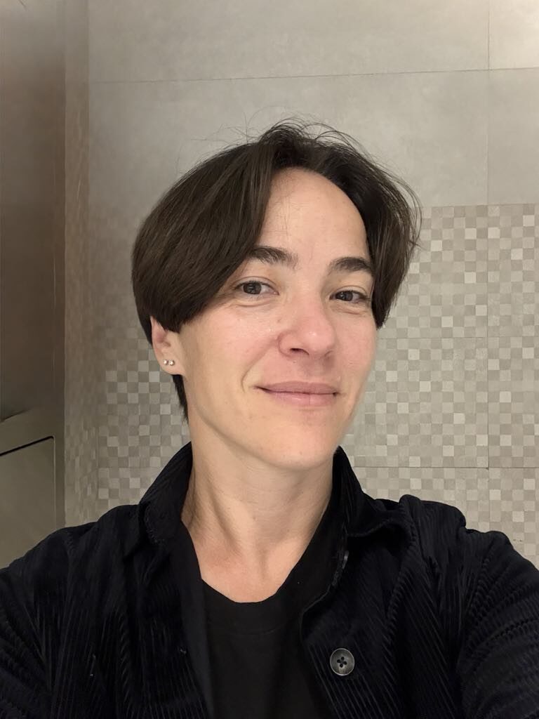 LGBTIQ* in der Ukraine: weibliche Person mit kurzen Haaren und dunkler Kleidung lächelt in die Kamera