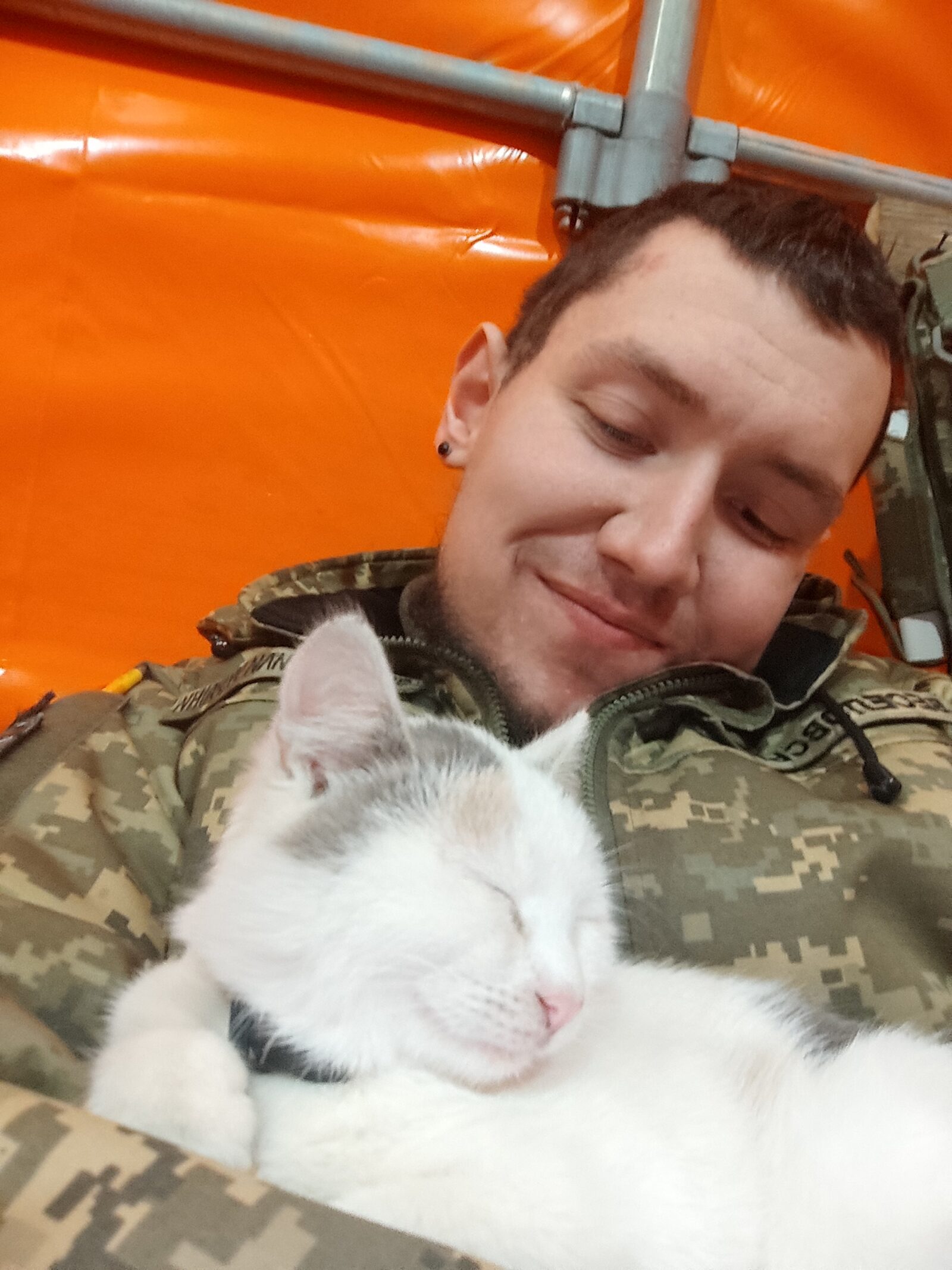 LGBTIQ* in der Ukraine: Soldat in ukrainischer Uniform hält eine Katze im Arm und lächelt