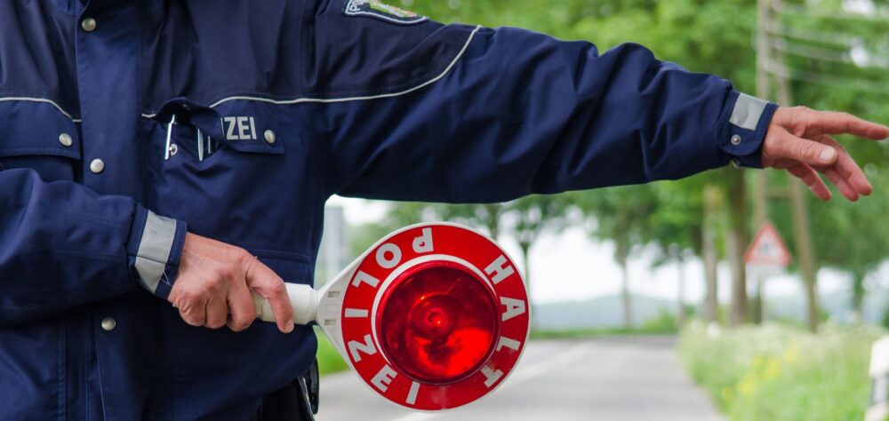 Symbolbild HIV bei der Polizei: polizist winkt auto mit Stopschild aus dem verkehr