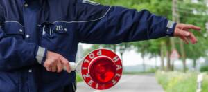 Symbolbild HIV bei der Polizei: polizist winkt auto mit Stopschild aus dem verkehr