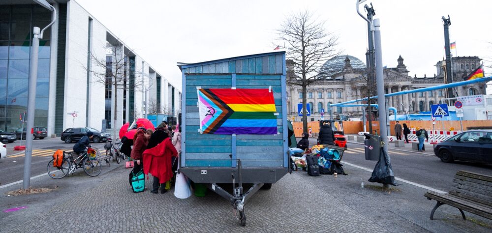 Ein Saunawagen mit Regenbogenflagge steht zwischen Paul-Löbe-Haus und Bundestag