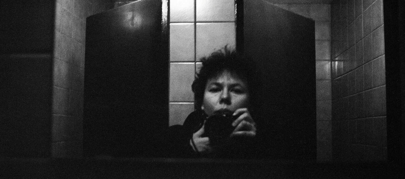 schwarz-weiß Selbstporträt in einem gekachelten Raum vor dem Spiegel