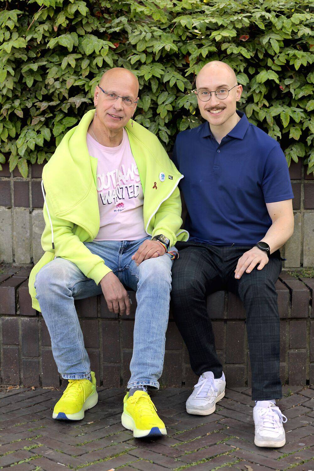Die beiden Interviewten sitzen lächelnd nebeneinander auf einer Parkbank.