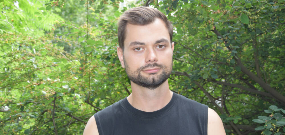 Porträt von Borys Hrachov im schwarzen Top vor grünen Bäumen