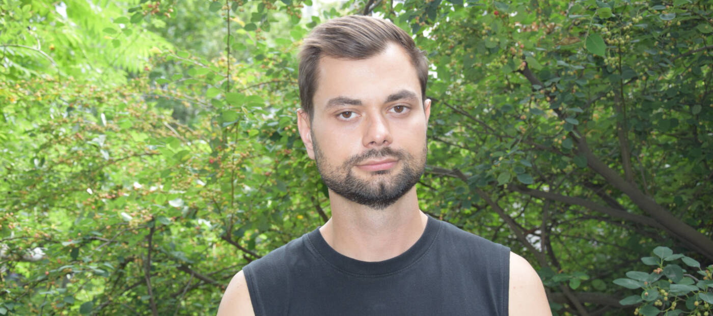 Porträt von Borys Hrachov im schwarzen Top vor grünen Bäumen