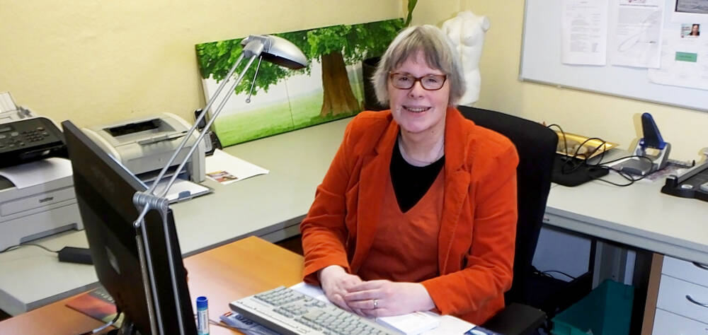 Person im roten Kostüm sitzt am Schreibtisch