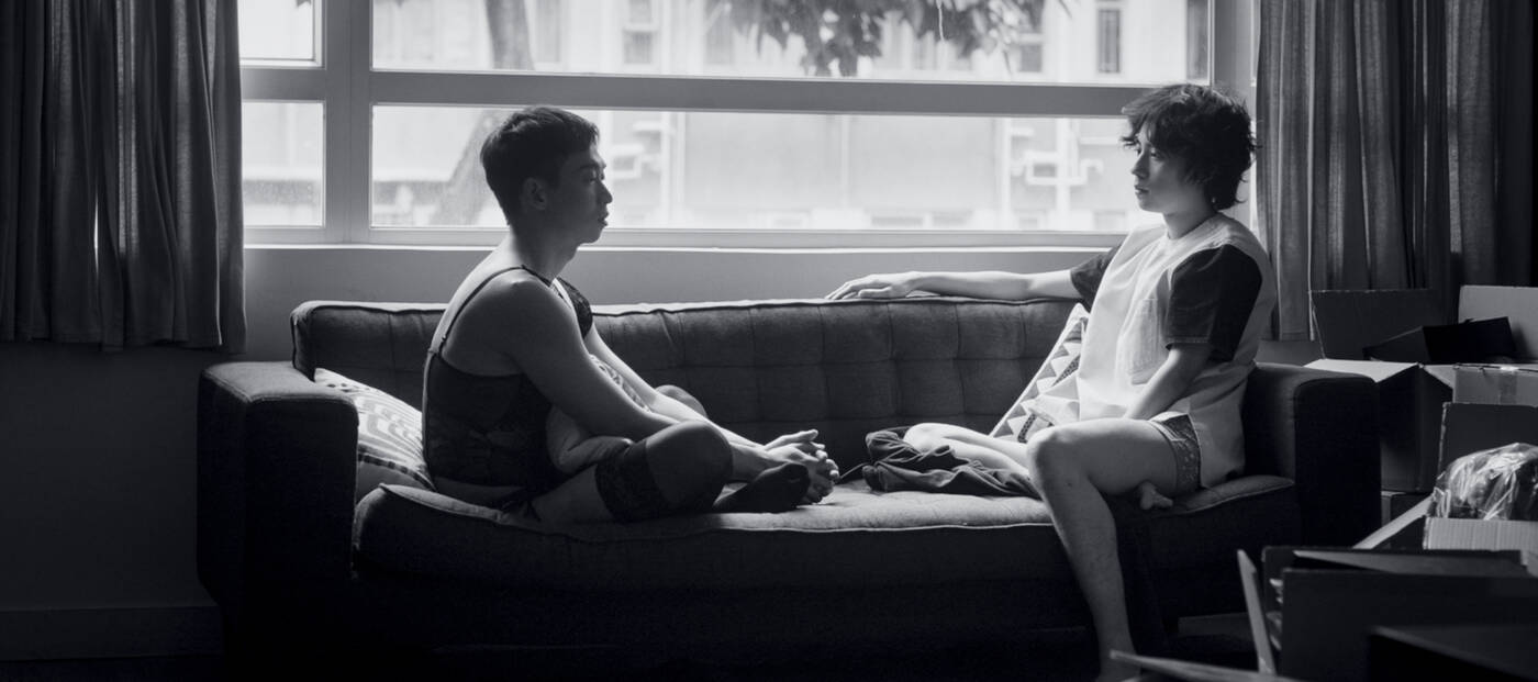 Schwarz-weiß-Foto: zwei junge Männer sitzen auf einem Sofa vor einem Fenster