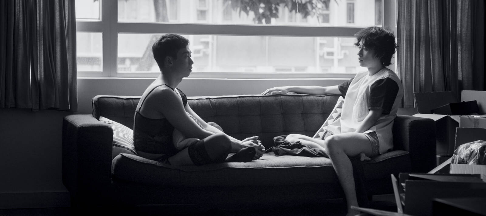 Schwarz-weiß-Foto: zwei junge Männer sitzen auf einem Sofa vor einem Fenster