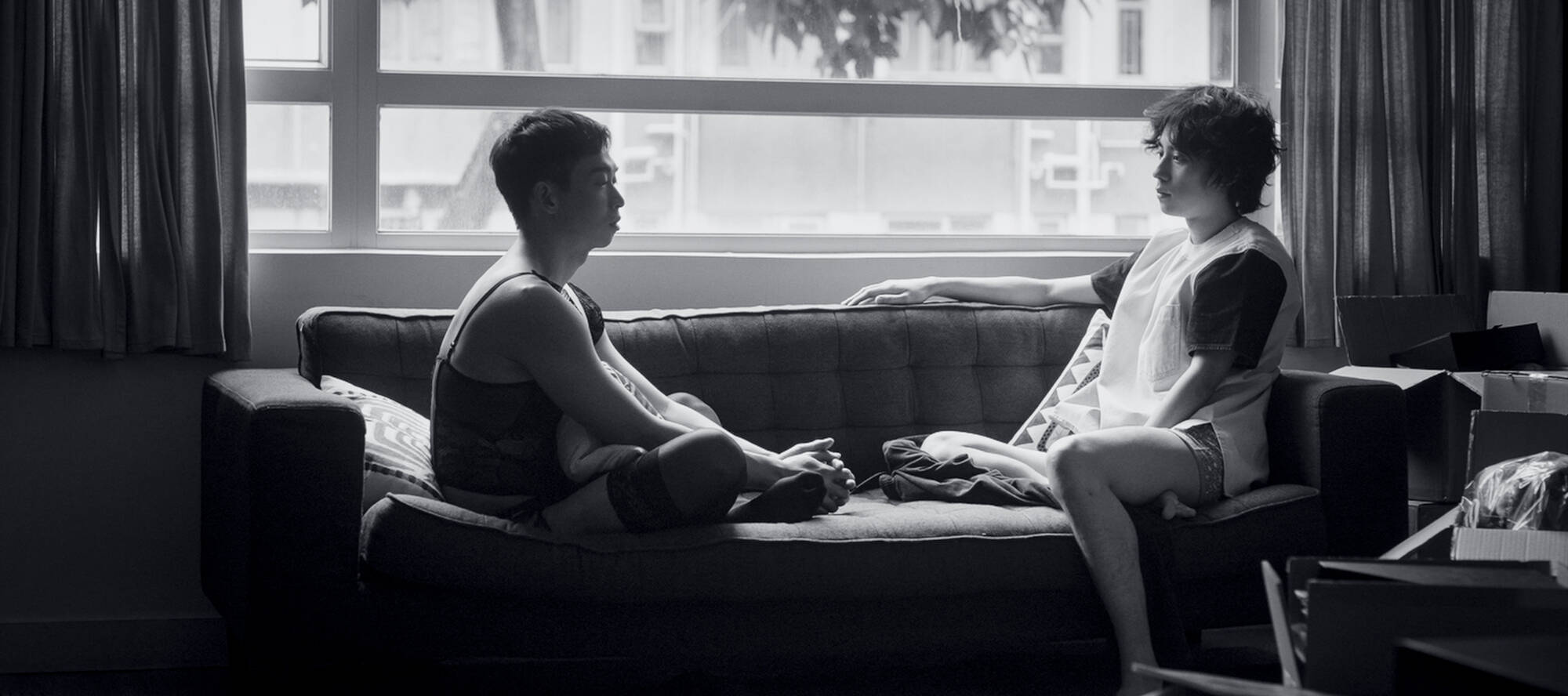 Schwarz-weiß-Foto: zwei junge Männer sitzen auf einem Sofa vor einem Fenster