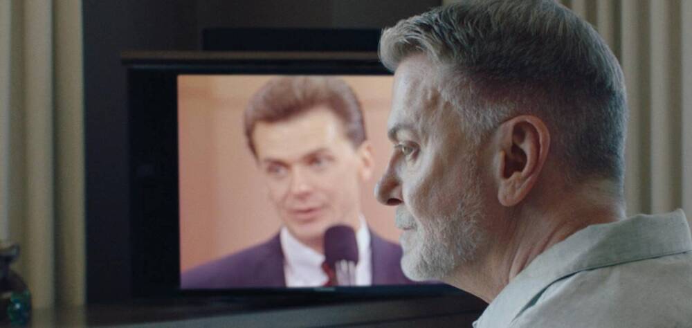 Mann im Profil vor einem Fernsehbildschirn, auf dem er in jüngeren Jahren zu erkennen ist