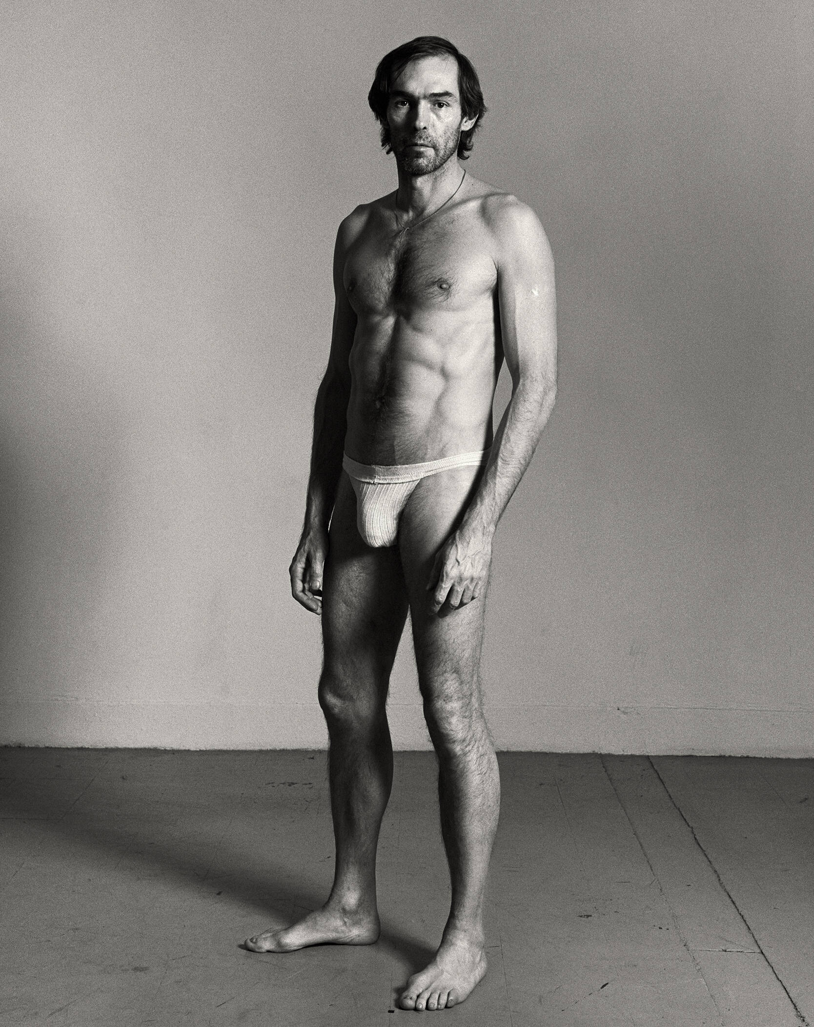 Porträt eines Mannes in Unterhose vor einer Wand stehend