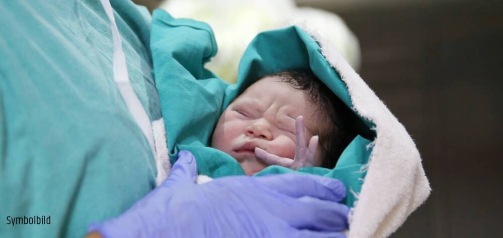 Neugeborenes Baby in den Armen einer Pflegekraft