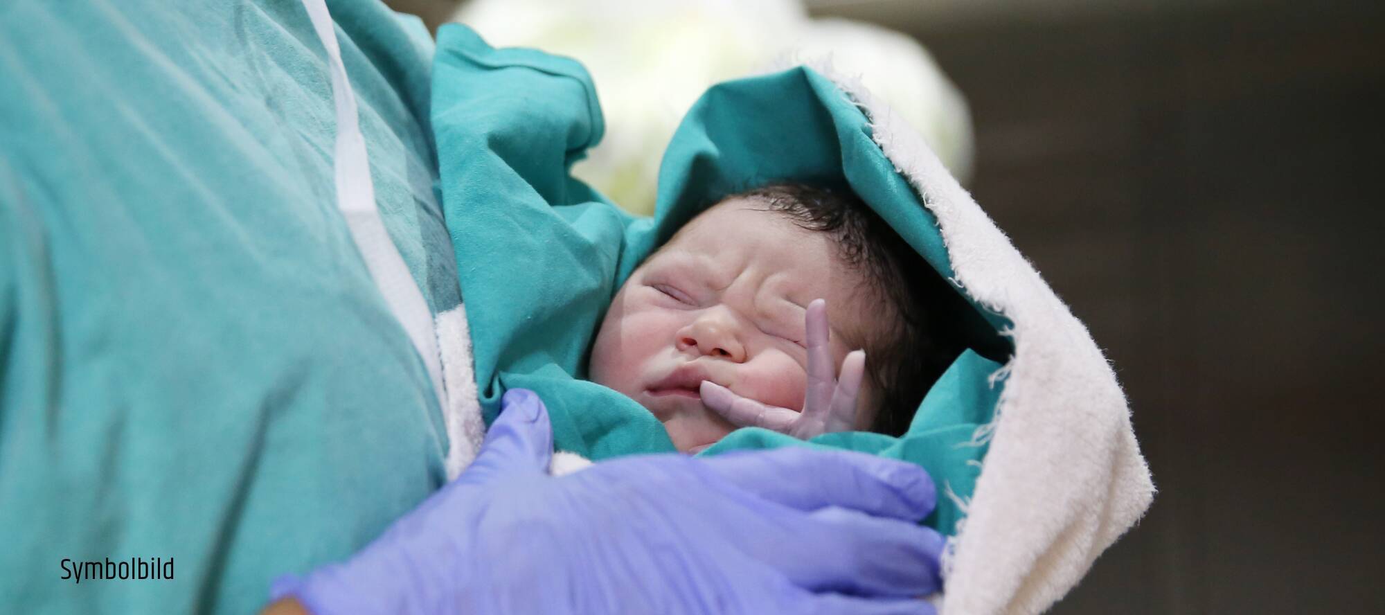 Neugeborenes Baby in den Armen einer Pflegekraft