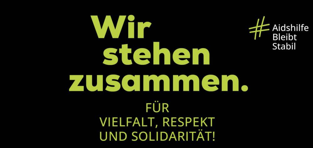 Blaue Schrift auf schwarzen Hintergrund: Wir stehen zusammen. Für Vielfalt, Respekt und Solidarität! Hashtag Aidshilfe Bleibt Stabil. Deutsche Aidshilfe