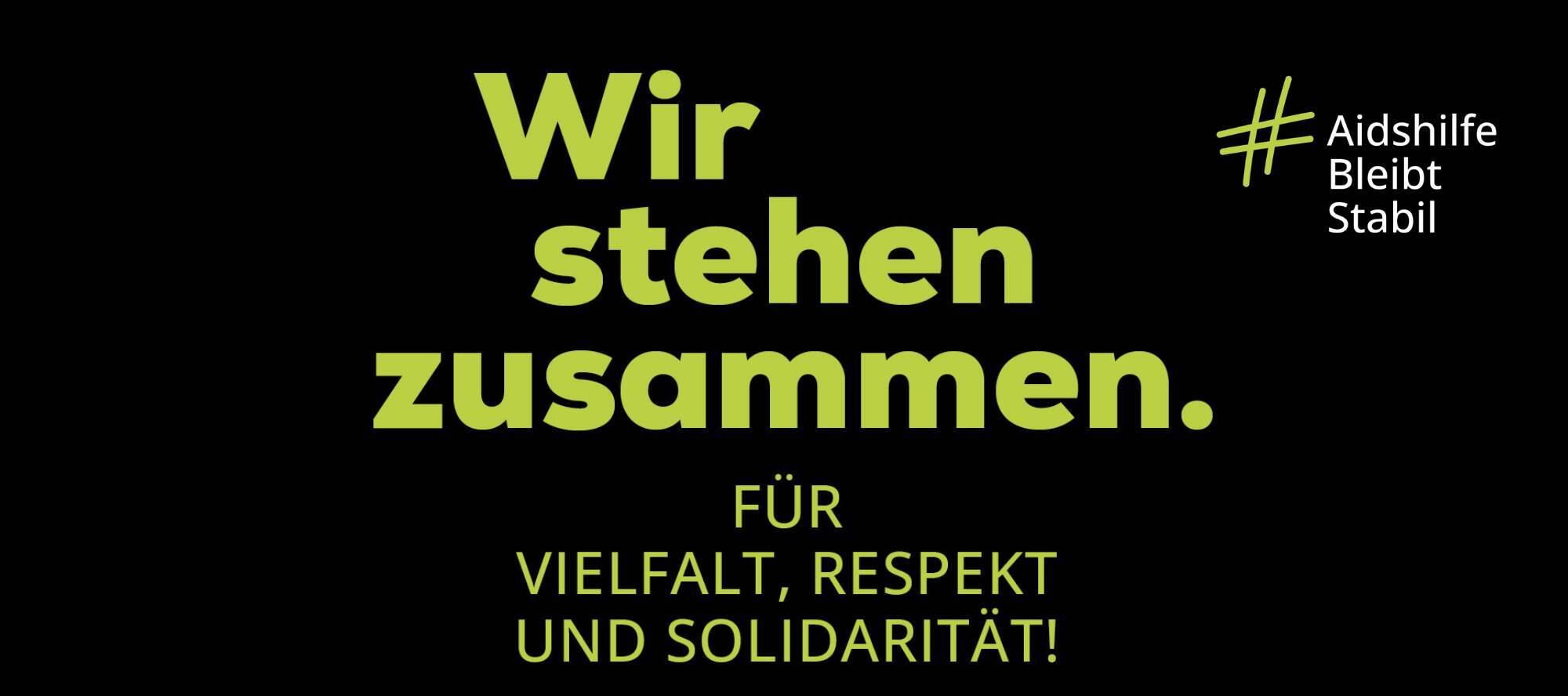 Blaue Schrift auf schwarzen Hintergrund: Wir stehen zusammen. Für Vielfalt, Respekt und Solidarität! Hashtag Aidshilfe Bleibt Stabil. Deutsche Aidshilfe