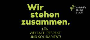 Blaue Schrift auf schwarzen Hintergrund: Wir stehen zusammen. Für Vielfalt, Respekt und Solidarität! Hashtag Aidshilfe Bleibt Stabil. Deutsche Aidshilfe