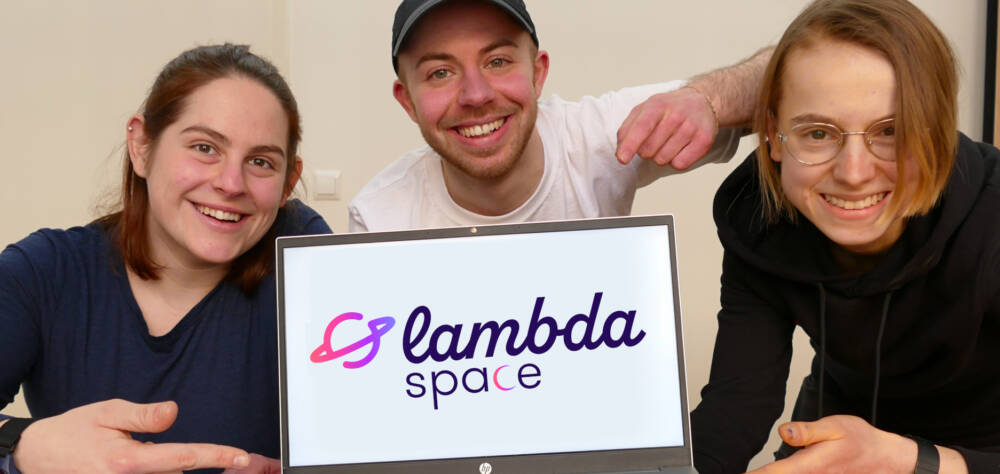 3 Personen mit einem Laptop, auf dem Bildschirm das Logo von lambda space