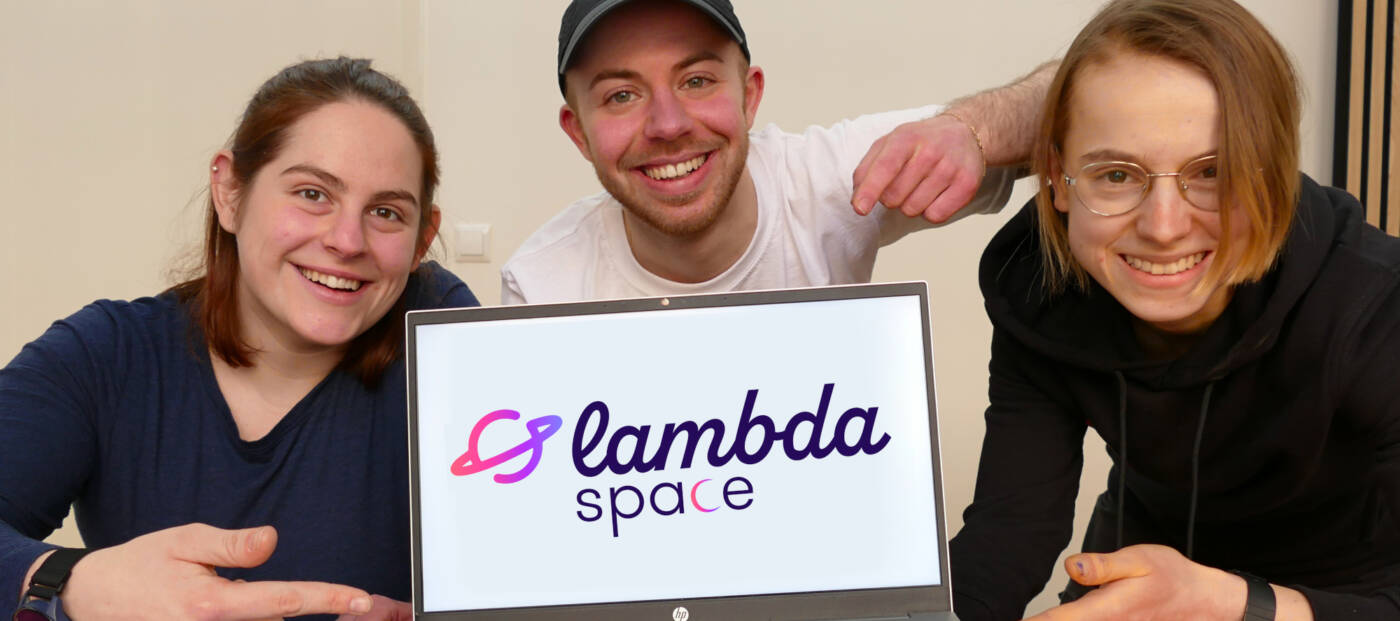 3 Personen mit einem Laptop, auf dem Bildschirm das Logo von lambda space