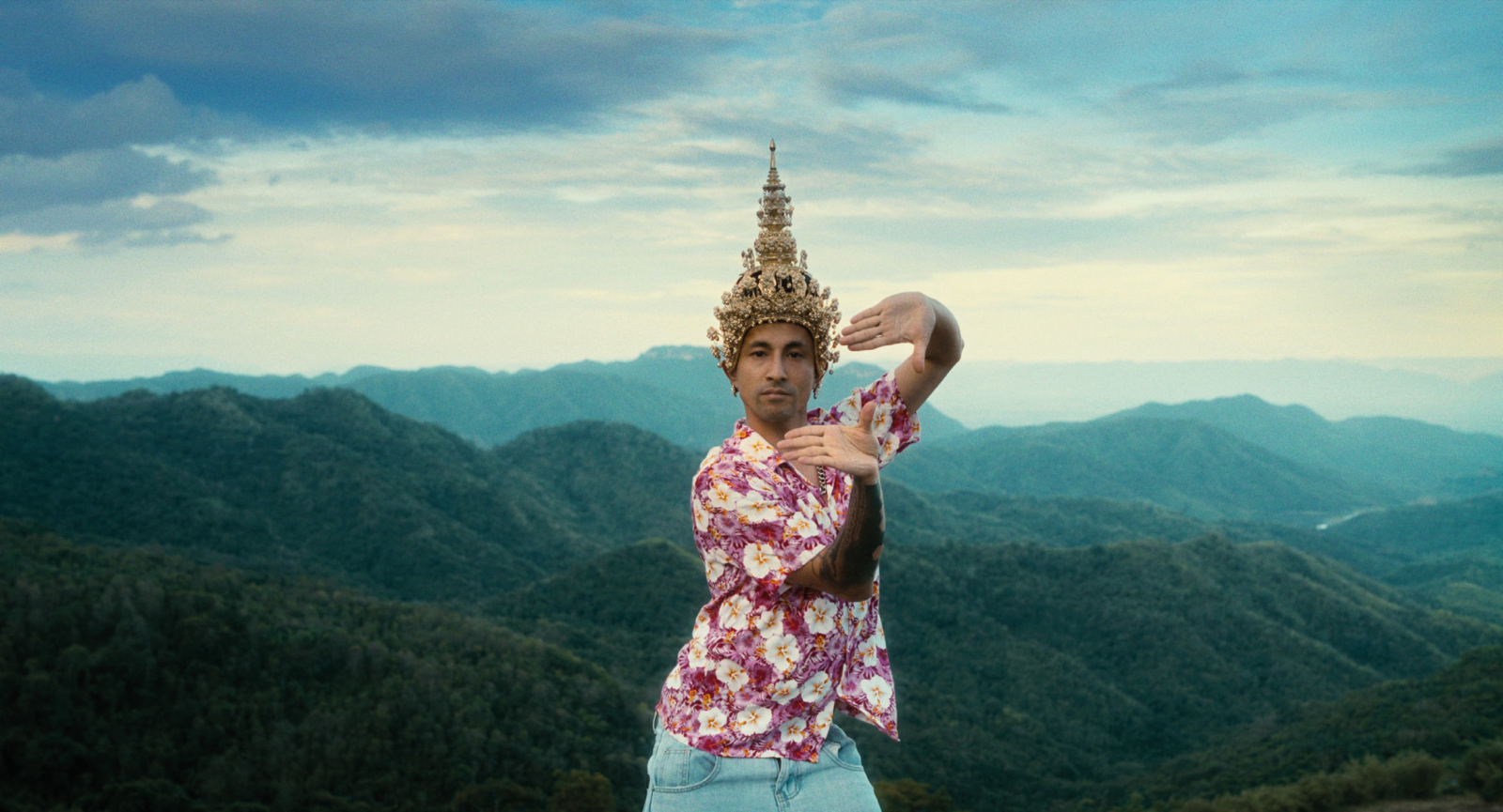 Person tanzt in traditioneller thailändischer Kleidung vor einer Berglandschaft